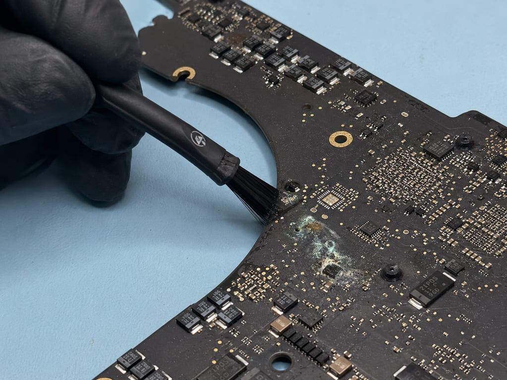 Technician at eRepair in Wicker Park inspecting a liquid-damaged MacBook logic board under magnification